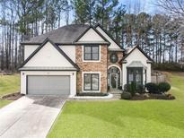 Charming two-story home featuring a stone facade, two-car garage, and manicured lawn at 9811 Spyglass Dr, Villa Rica, GA 30180