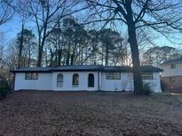 Charming single-story home featuring a brick facade, arched entryway and mature trees on a landscaped lot at 1055 Pinecrest Dr, Forest Park, GA 30297