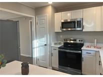 This kitchen features white cabinets, modern appliances, and a view to the next room at 1055 Pinecrest Dr, Forest Park, GA 30297