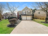 Charming home featuring a two-car garage, landscaped yard, and traditional architectural details at 2750 Dominion Walk Ln, Snellville, GA 30078