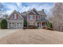Charming two-story home featuring a well-manicured lawn, red window shutters, and a classic architectural design at 5830 Wild Azalea Cv, Sugar Hill, GA 30518