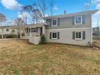 Charming two-story home featuring a white brick facade, green siding, and covered carport at 332 Hickory Acres Se Dr, Smyrna, GA 30082