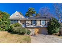 Tan home with a gabled roof, manicured shrubs, and a two-car garage at 5876 Old Wellborn Trce, Lithonia, GA 30058