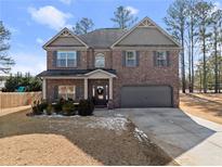 Charming brick two-story home with attached garage and manicured front lawn at 1323 Champion Run Dr, Dacula, GA 30019