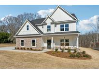 Charming two-story home with a stone facade, white siding, a covered porch, and a well-maintained lawn at 6035 Hendrix Rd, Cumming, GA 30040