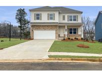 Two-story home with a stone veneer, two-car garage, a long driveway, and manicured lawn at 154 Calla Dr, Douglasville, GA 30134