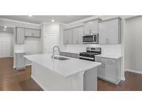 Beautiful kitchen with gray cabinets, stainless steel appliances, and a large island with a quartz countertop at 404 Village Ln, Fairburn, GA 30213