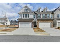 Charming two-story townhome featuring brick accents, attached two-car garage, and well-manicured landscaping at 1883 Frisco Way, Suwanee, GA 30024