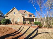 Charming two-story home with a covered porch, stone facade, manicured lawn, and mature trees at 1526 Rocky River Dr, Lawrenceville, GA 30045