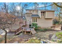 Unique two-story home featuring a wooden deck and stone accents surrounded by mature trees and landscaping at 3791 Oxford E Way, Marietta, GA 30062