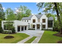 Elegant, all white brick home with black window frames, three-car garage, and professionally landscaped front yard at 42 Blackland Nw Rd, Atlanta, GA 30342