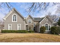 Charming two-story home with a manicured lawn and gray stucco exterior at 12015 Wildwood Springs Dr, Roswell, GA 30075