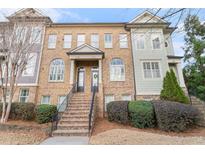 A brick townhome featuring a landscaped front yard and a set of stairs leading to the front door at 2447 Gatebury Cir, Chamblee, GA 30341