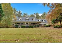 Charming white farmhouse with a wraparound porch and mature trees in a spacious yard at 1035 Dorris Rd, Douglasville, GA 30134