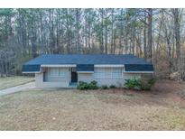 Ranch-style home features a brick facade, dark roof and door, trimmed bushes, and a lush, wooded landscape at 645 Plainville Sw Dr, Atlanta, GA 30331