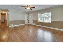 Spacious living room features hardwood floors and a ceiling fan at 4567 Duncan Dr, Sugar Hill, GA 30518