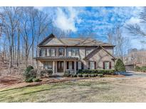 Beautifully landscaped front yard with a charming two-story home, featuring a covered porch at 6225 Leeward Tide Ct, Cumming, GA 30041