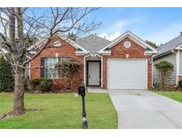 Charming one-story red brick home featuring a well-manicured front lawn and a one car garage at 621 Shadow Lake Dr, Lithonia, GA 30058