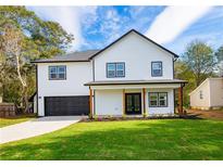 Charming two-story home with black trimmed windows, a well-manicured lawn and inviting, covered front entry at 221 Cobb St, Palmetto, GA 30268