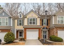 Charming townhome with a brick front, attached garage, and well-maintained landscaping at 295 Kigian Trl, Woodstock, GA 30188