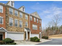 Brick townhouse with attached garages, trimmed bushes and front door entry, on a sunny day with blue skies at 4662 Creekside Villas Se Way, Smyrna, GA 30082