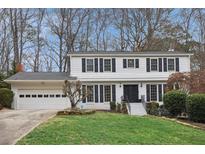 Charming two-story home with a well-manicured lawn, black shutters, and an attached garage at 1524 Chateau Dr, Dunwoody, GA 30338