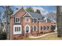 Beautiful brick home with a well-manicured lawn, black shutters, and lush landscaping at 10440 Cranchester Way, Alpharetta, GA 30022