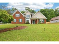 Charming two-story home featuring a well-manicured lawn and a mix of brick and siding accents at 3641 Willow Club Dr, Loganville, GA 30052