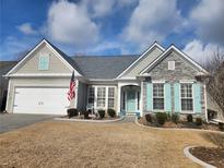 Charming single-story home with stone accents, blue shutters, manicured landscaping, and an American flag at 912 Santa Anita Dr, Woodstock, GA 30189