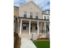 Charming two-story townhome boasts a light brick facade, covered porch, and well-manicured lawn at 110 Chiswick Cir # 40, Alpharetta, GA 30009