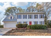 Charming two-story home with a red front door and blue shutters surrounded by lush landscaping on a sunny day at 615 Heartwood Se Way, Conyers, GA 30094