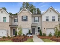 Charming townhomes featuring brick and siding exteriors, two-car garages, and professionally landscaped front yards at 308 Navigator Ln, Mcdonough, GA 30253