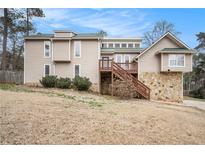 Two-story home featuring stone accents, wood deck and siding, and a sloped front yard at 4962 Preswick Ne Ct, Marietta, GA 30066