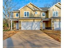 New construction townhome features a two-car garage and yellow siding at 6860 Robinson St, Lithonia, GA 30058