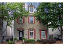 Charming home featuring red shutters, brick arches, and manicured landscaping around the front at 319 Barbados Ln, Suwanee, GA 30024