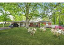 Charming single-story home with a lush green lawn, flowering bushes, and a convenient carport at 4033 Louise St, Powder Springs, GA 30127