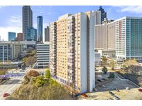 Exterior view of high-rise apartment building in the city, parking lot, and bridge in the foreground at 215 Piedmont Ne Ave # 308, Atlanta, GA 30308