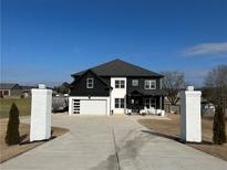 Striking two-story modern farmhouse featuring a black and white exterior, long driveway and a two-car garage at 557 Loth Wages Rd, Dacula, GA 30019