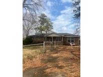 Traditional brick home with a covered porch and a spacious front yard with some trees at 7144 Carolyn Cir, Lithia Springs, GA 30122