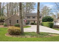 Charming two-story home features a stone facade, mature trees, circular drive, and a well-manicured lawn at 7405 Princeton Trce, Atlanta, GA 30328