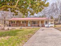 Charming brick ranch-style home with a red metal roof and a spacious front yard with mature tree. Basketball court on the side at 283 Reynolds Bridge Rd, Kingston, GA 30145