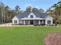 Stunning modern farmhouse featuring a covered front porch, black trim windows, and a lush green lawn at 3911 Peeksville Rd, Locust Grove, GA 30248