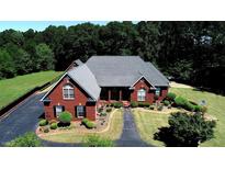Beautiful brick home with manicured landscaping, mature trees, and an asphalt driveway at 5780 Warren Farm Sw Rd, Powder Springs, GA 30127