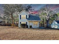 Charming two-story home featuring a cozy front porch and classic architectural details, nestled in a serene landscape at 7747 Rountree Xing, Riverdale, GA 30274