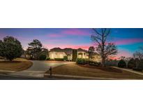 Stunning single-story home at dusk with manicured lawn, elegant architecture, and long drive at 1069 Eagles Brooke Dr, Locust Grove, GA 30248