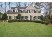 Charming two-story home with lush front lawn, manicured landscaping, black shutters, and inviting entrance at 12090 Lonsdale Ln, Roswell, GA 30075