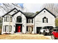 Charming two-story painted brick home with a striking red door, black trim and multi-pane windows at 559 Fairway Dr, Woodstock, GA 30189