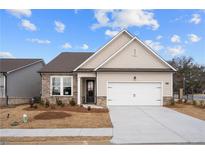 Charming home featuring stone accents, neutral siding, well-manicured lawn and two-car garage at 1723 Juniper Berry Way, Loganville, GA 30052