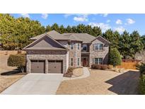 Charming two-story home with a brick and stone facade, complemented by a well-manicured lawn and a two-car garage at 3830 Deer Run Dr, Cumming, GA 30028