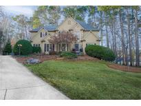 Charming two-story home with a stone facade, manicured lawn, and mature trees at 1165 Pin Oak Ct, Cumming, GA 30041